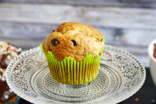 Muffins moelleux aux pépites de chocolat présentés dans une caissette verte sur un plat en verre