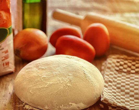 Comment faire une pâte à pizza maison en 5 étapes. Boule de pâte à pizza farinée, tomates, rouleau et huile d'olive