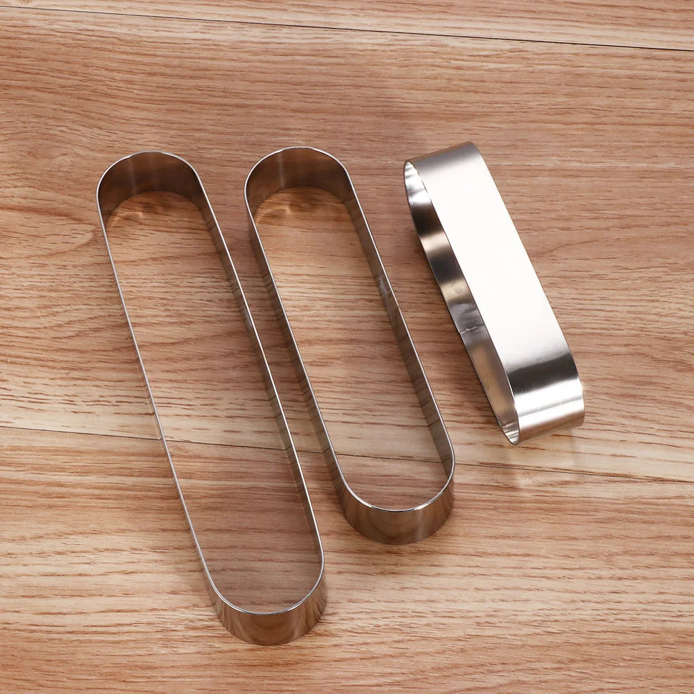 Moule à Gâteau et Tartelette Inox – Durable & Éco. Trois emporte-pièces ovales en inox sur planche en bois