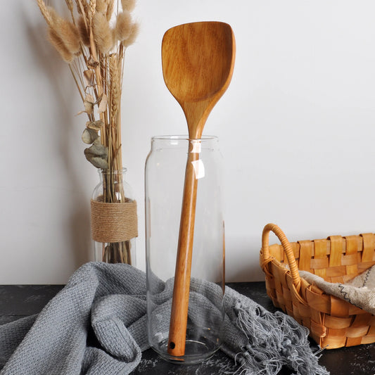 Spatule en Bois Long Manche – Ustensile de Cuisine Durable. Spatule en bois dans un bocal en verre sur tissu gris et panier tressé