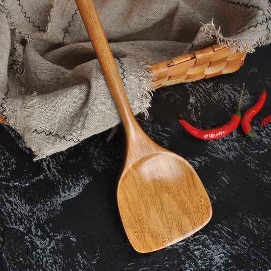 Spatule en Bois Long Manche – Ustensile de Cuisine Durable en teck, manche long, posée sur ardoise avec linge et piment