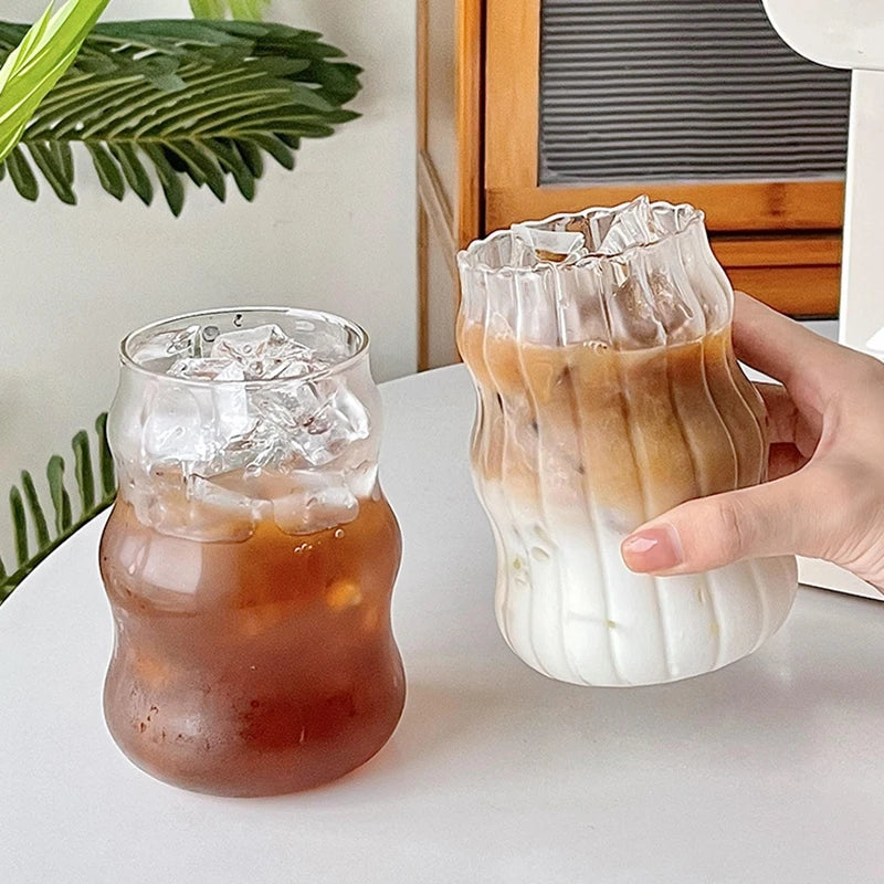 Verre Tumbler Ondulé Transparent – Élégant & Pratique. Deux verres ondulés avec glaçons et café latte sur table