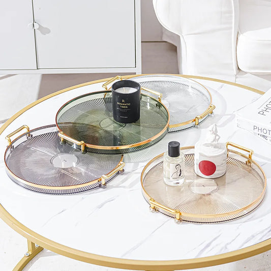 Plateau Rond Acrylique avec Poignées Dorées – Déco & Service. Quatre plateaux ronds transparents colorés sur table marbre