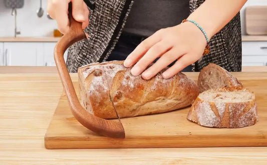 Couteau à Pain Inox – Sans Miettes & Manche Bois Confort coupant une miche de pain fraîche sur une planche en bois
