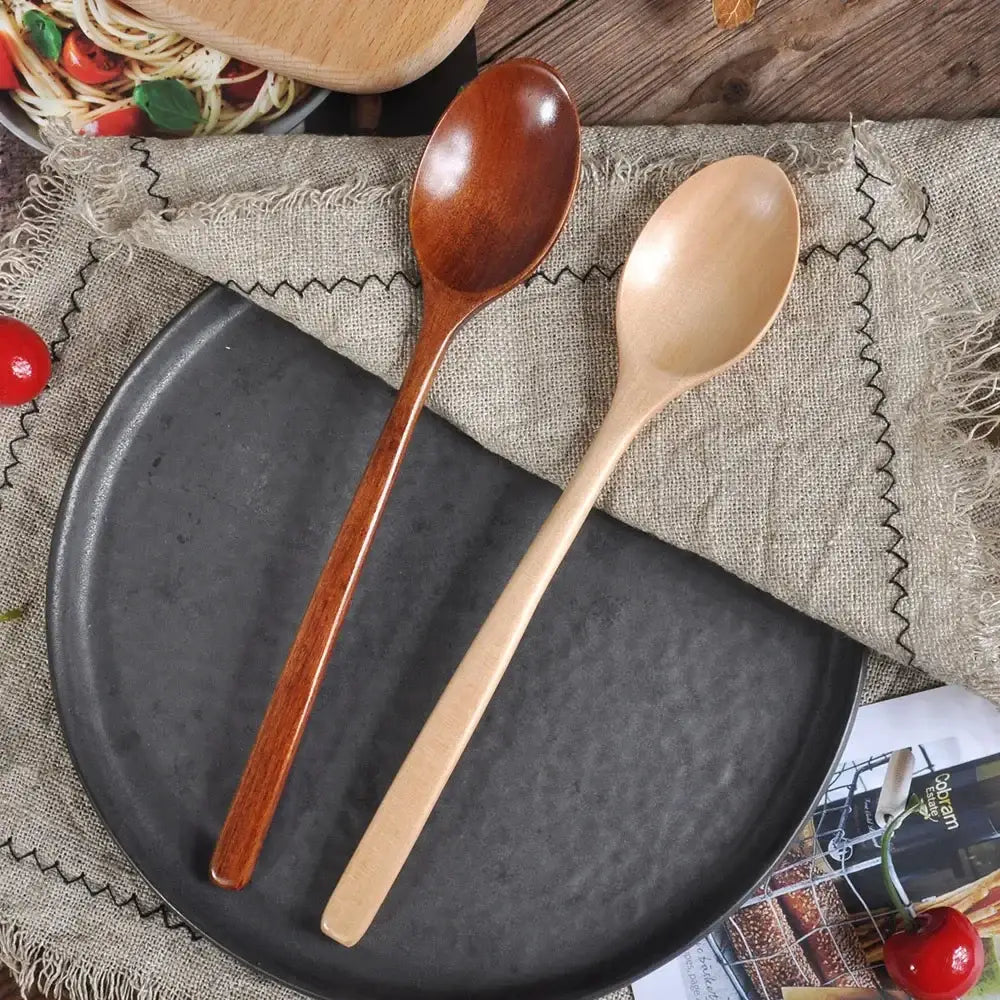 Cuillère en Bois Phoebe Ustensile Cuisine 23,5 cm en bois clair et foncé sur une assiette noire