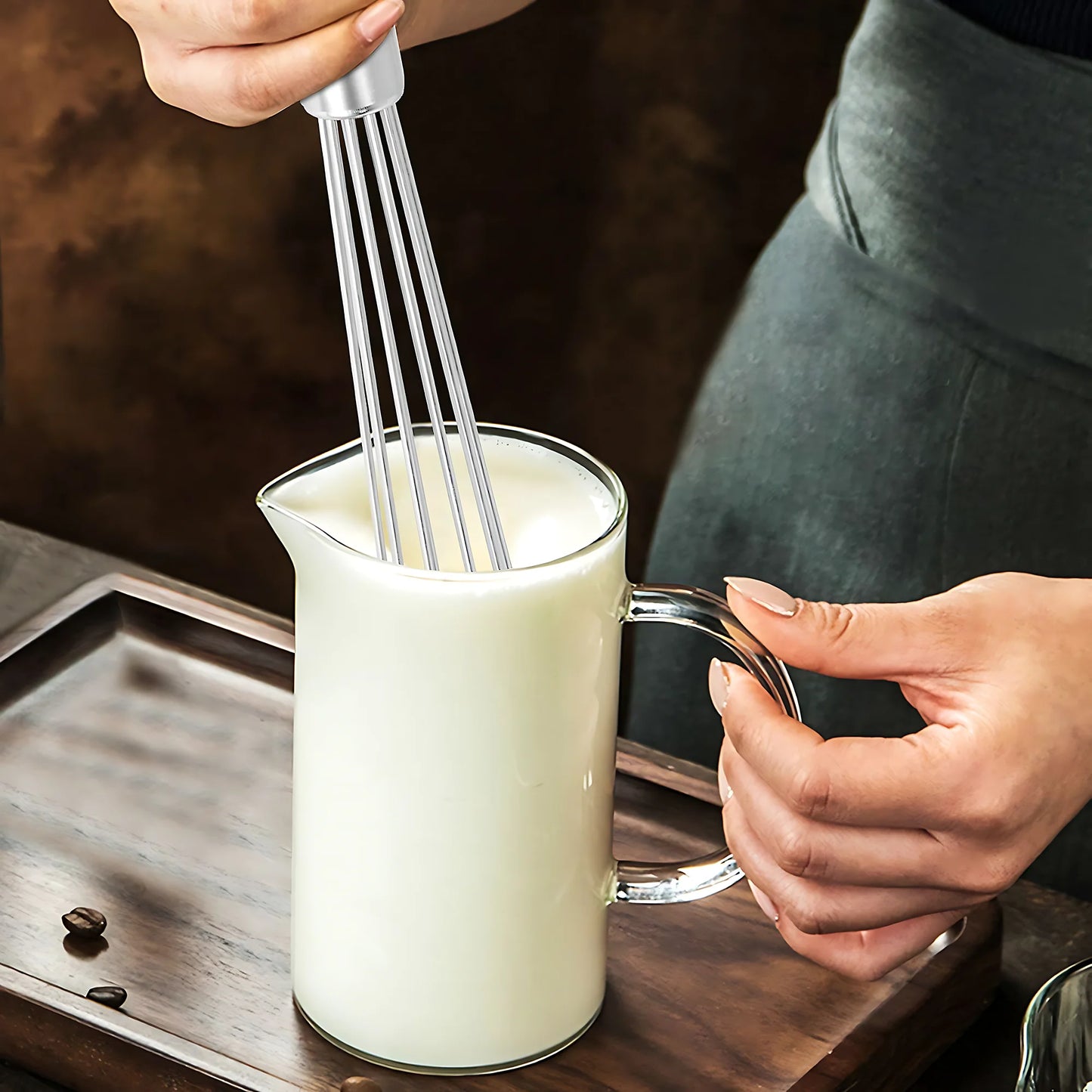 Main fouettant du lait dans un pichet en verre avec Fouet à œufs inox 304 - durable, éco-friendly et performant.