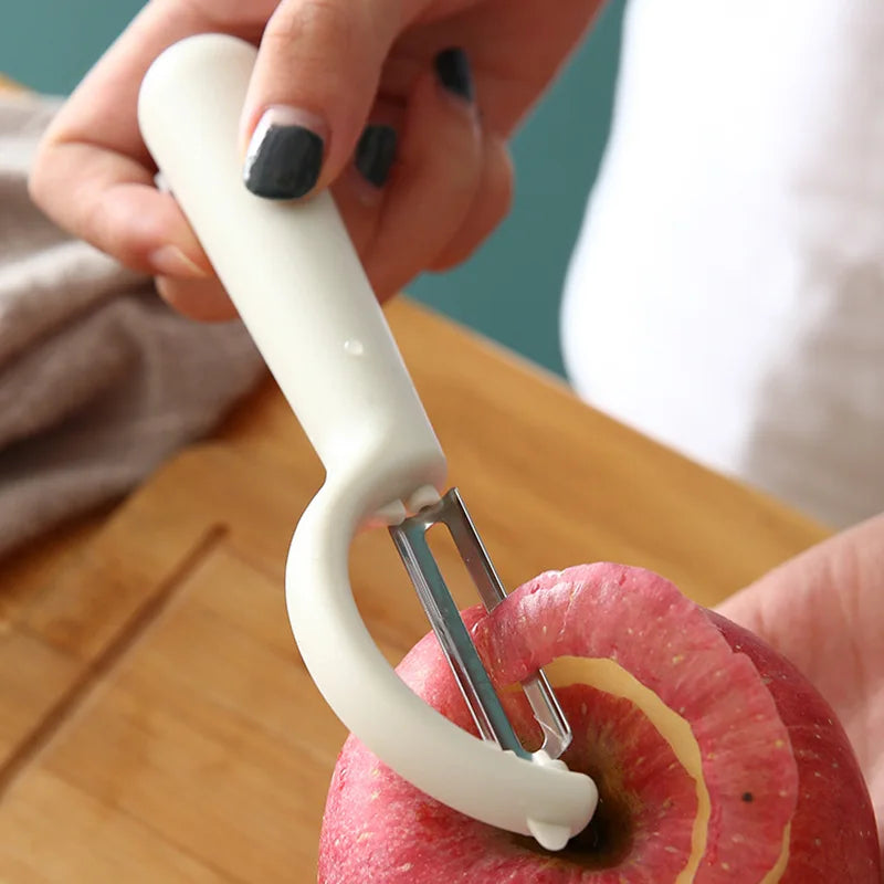 Éplucheur Inox Multifonction – Fruits Légumes Antidérapant utilisé pour peler une pomme rouge avec poignée blanche ergonomique