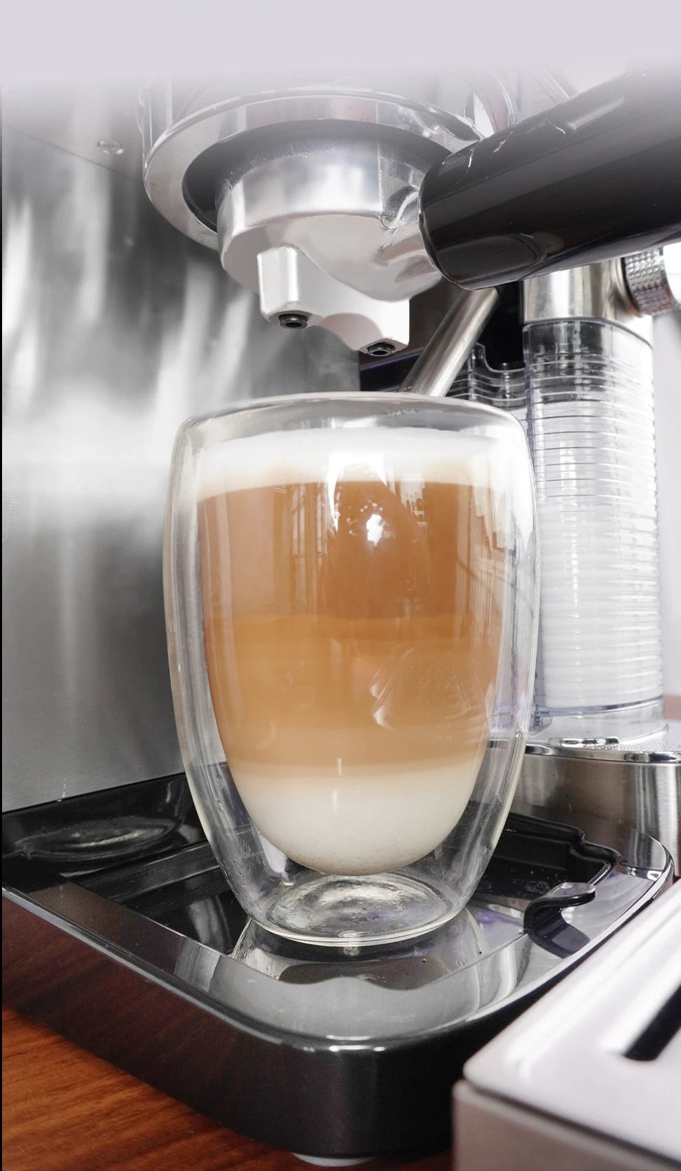 Machine à café expresso avec un verre à double paroi préparant un café latte crémeux