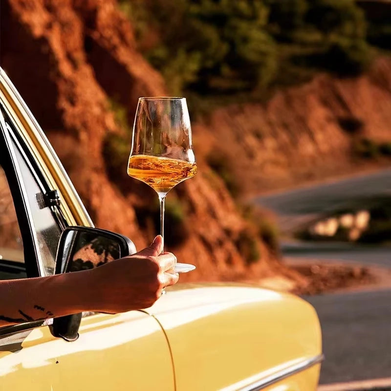Verres à Vin & Champagne JIUAN – Cristal 400-760 ml avec un verre dans une main près d'une voiture jaune