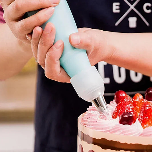 Personne utilisant Kit Douilles Pâtisserie Inox + Adaptateur – 5 à 20 pcs pour décorer un gâteau avec de la crème rose et des fruits