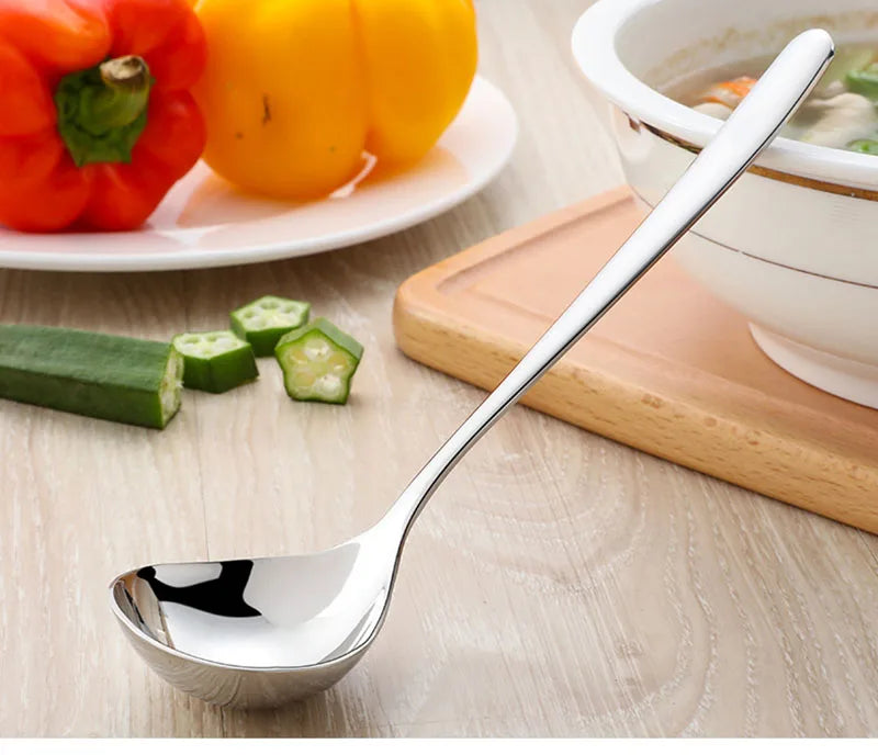 Louche Inox Épaissie – Manche Long en acier inoxydable posée sur une table à côté de légumes et d'un bol de soupe