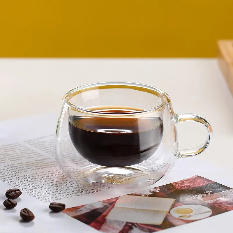 Tasse Double Paroi en Verre avec café noir sur une surface élégante et des grains de café autour