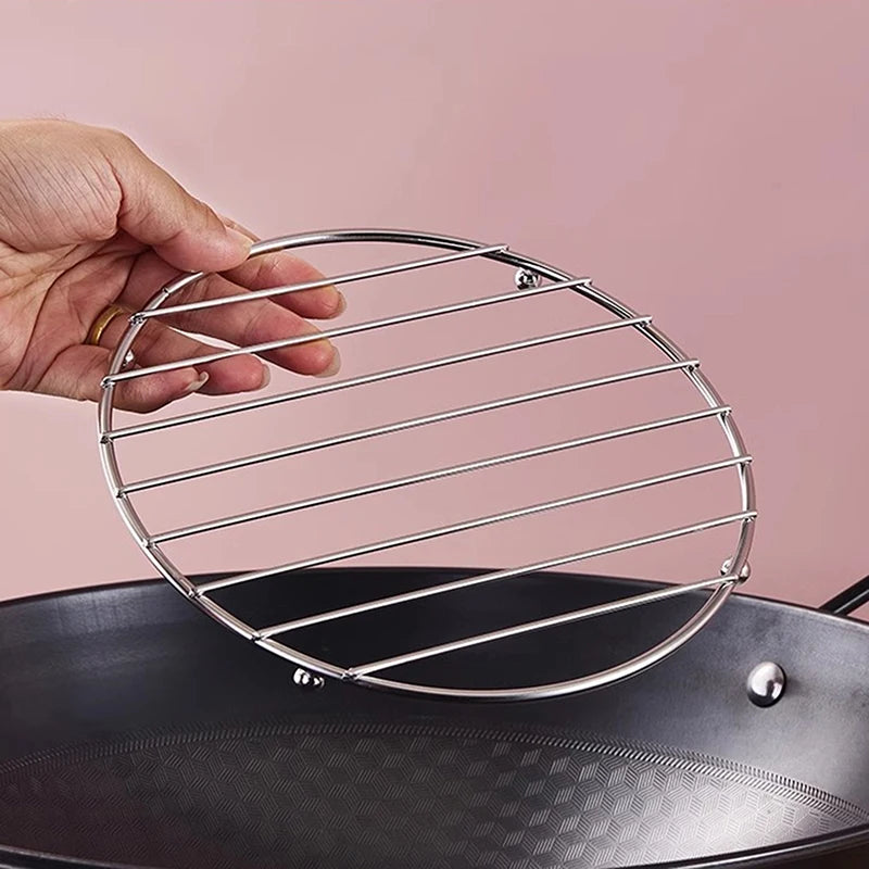 Sous-plats inox ronds et carrés – Protège et stylise votre cuisine. Sous-plat inox rond tenu à la main au-dessus d'une poêle.