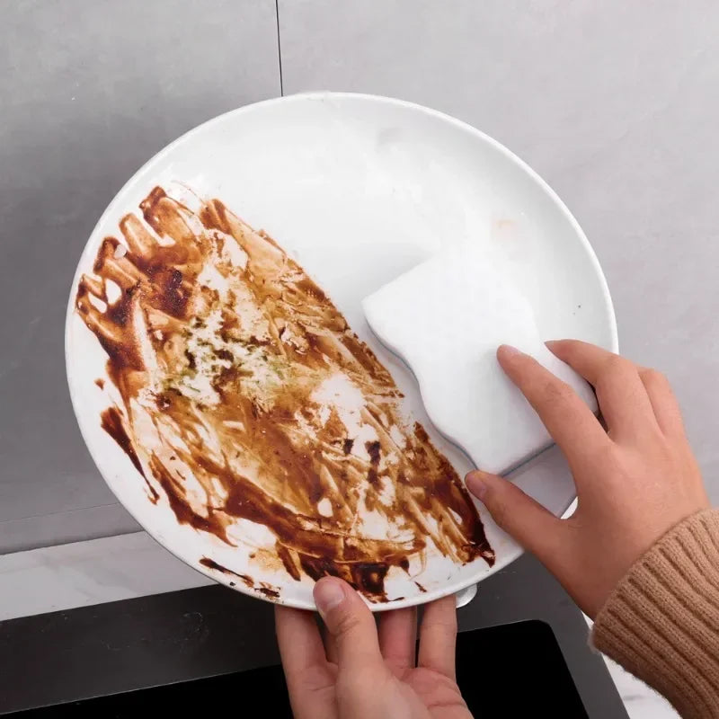 Assiette très salie en cours de nettoyage à la main avec Éponge magique – Lot de 50 pièces éco-friendly 10×6 cm.