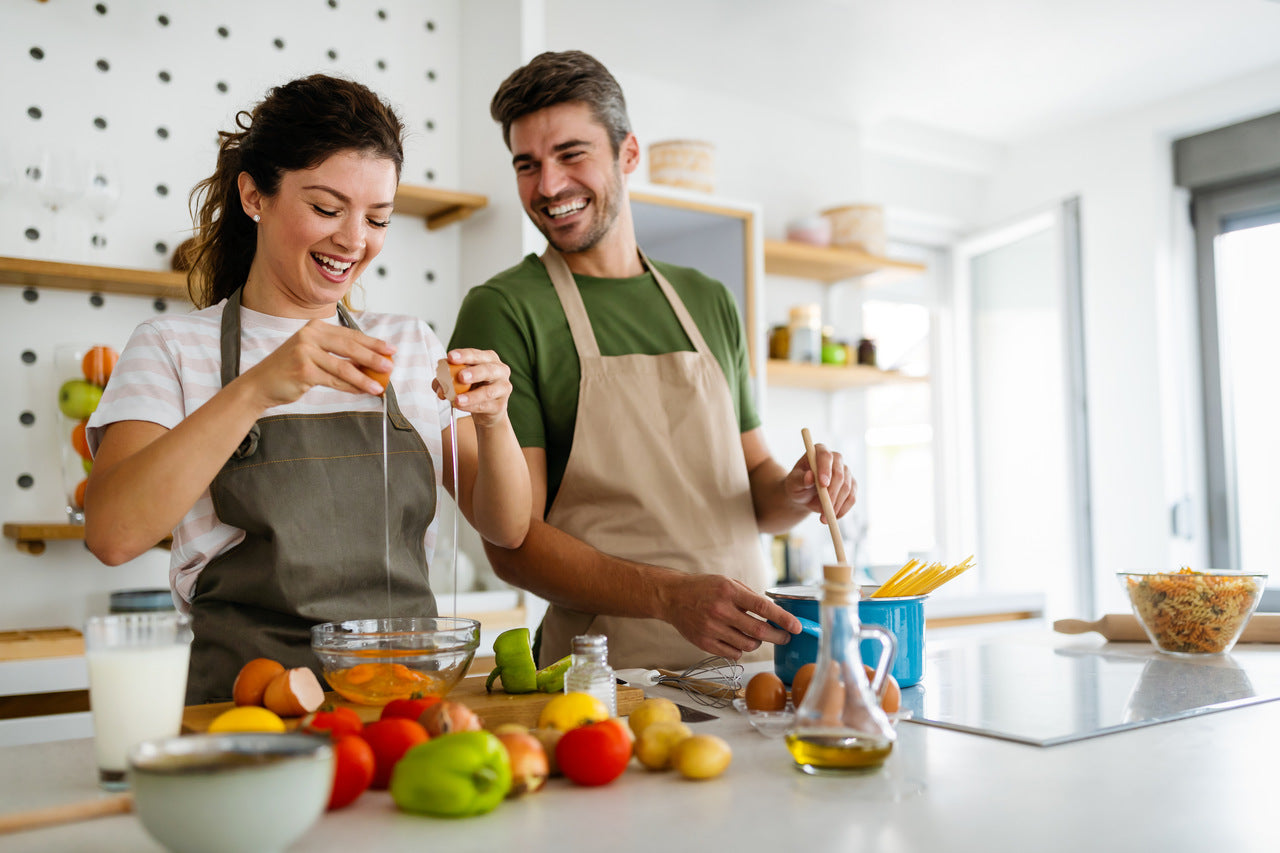 moment conviviale que partage un couple à cuisiner une recette dans une cuisine