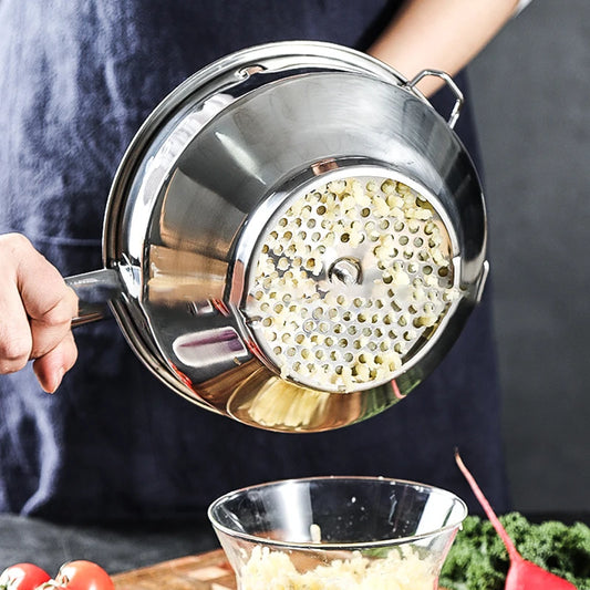 Moulin à légumes manivelle en acier inoxydable tenu au-dessus d'un bol en verre avec purée de légumes