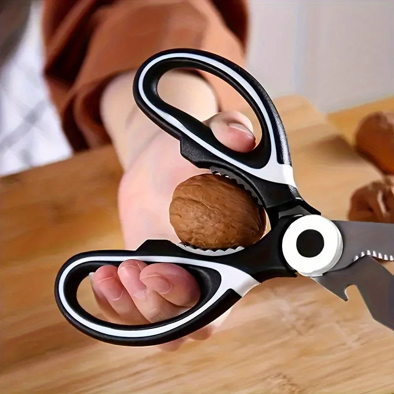 Ciseaux de Cuisine Multifonction noirs utilisés pour casser des noix sur une table en bois