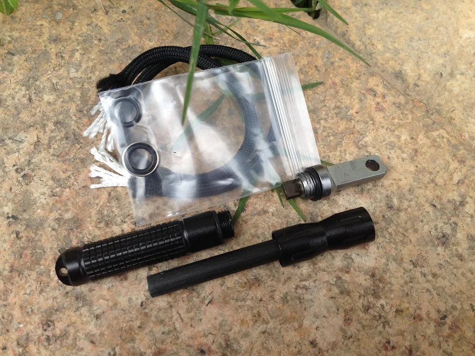 Pack Survie Solo 72h – Kit complet plus allume-feu et accessoires de survie noirs sur sol rocheux