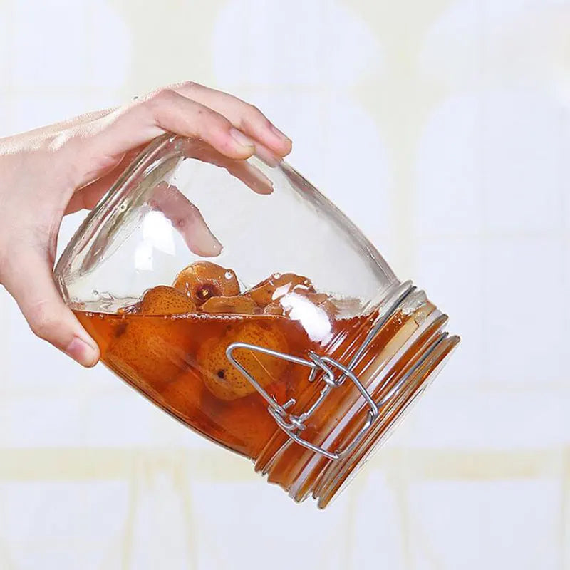 Mains tenant un pot de rangement hermétique en verre avec fruits en conserve à l'intérieur