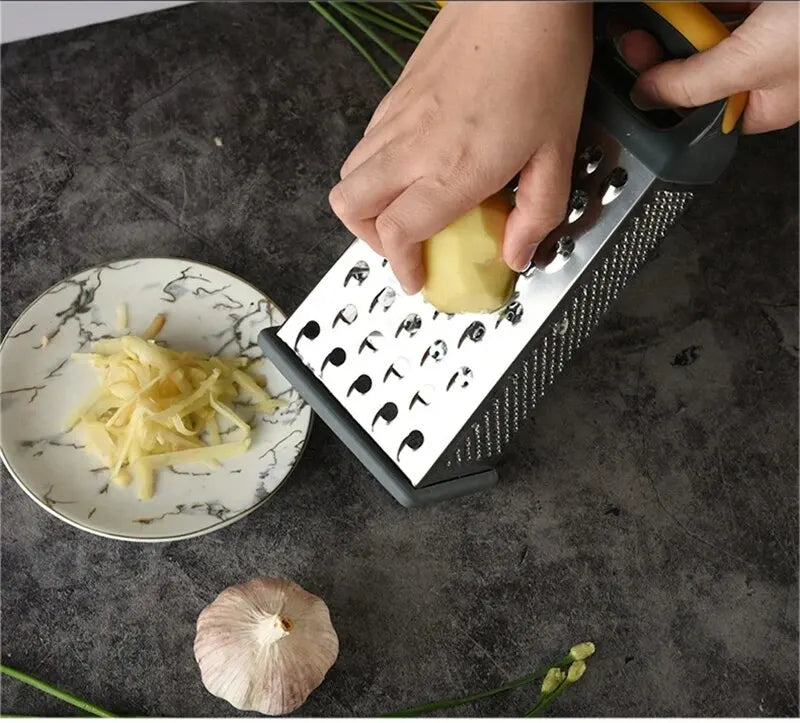 Râpe 4 Faces Inox – Polyvalente, Précise et Durable utilisée pour râper une pomme de terre au-dessus d'une assiette avec ail et herbes sur table