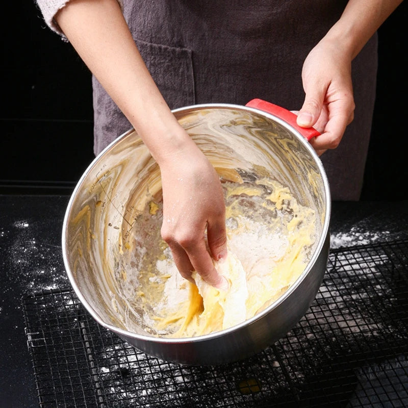 Personne mélangeant la pâte dans un saladier inox avec poignée rouge de Ustensile de chef