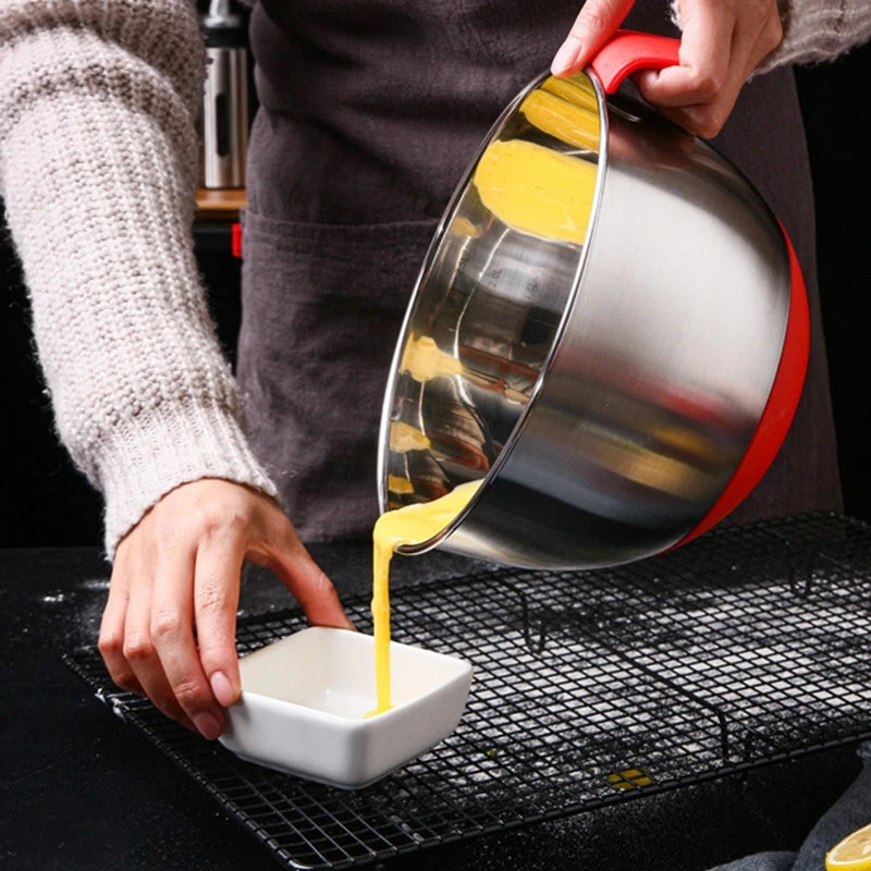 Saladiers Inox avec Couvercles et Râpes – Lot 3 Tailles versant une préparation jaune dans un bol blanc