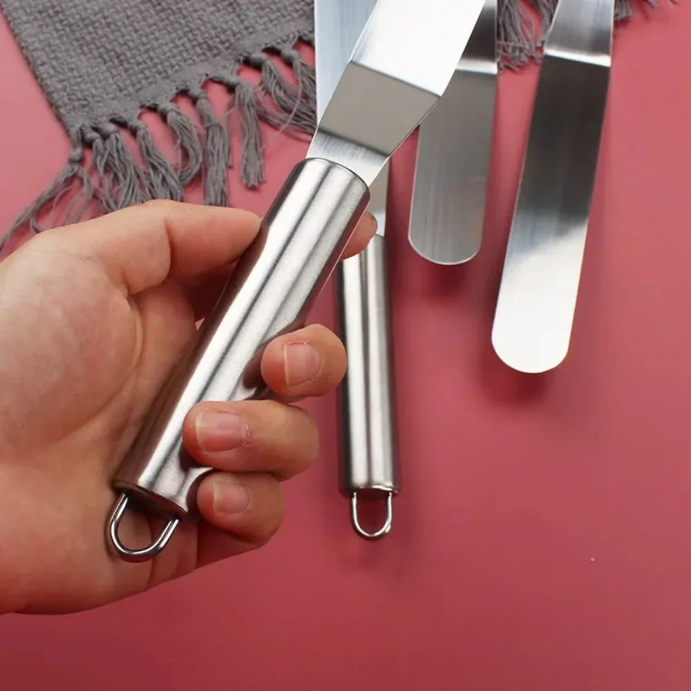 Spatule à Crème Inox avec manche en acier inoxydable tenue en main sur fond rose