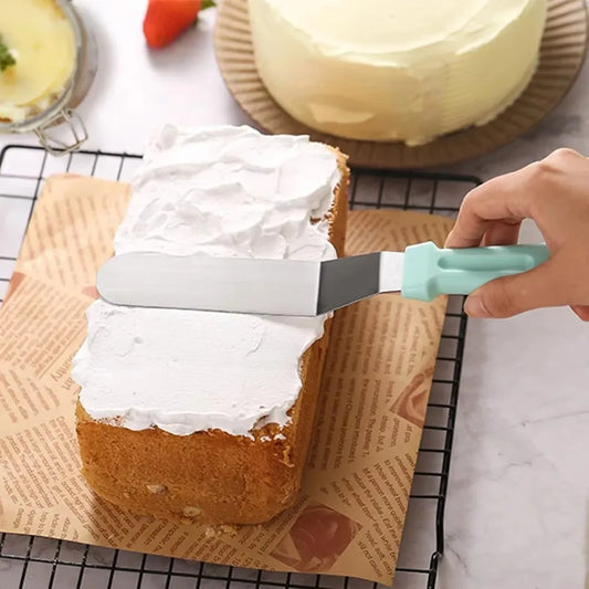 Spatule à Glaçage Inclinée en Acier Inoxydable avec manche bleu utilisée pour étaler du glaçage sur un gâteau rectangulaire