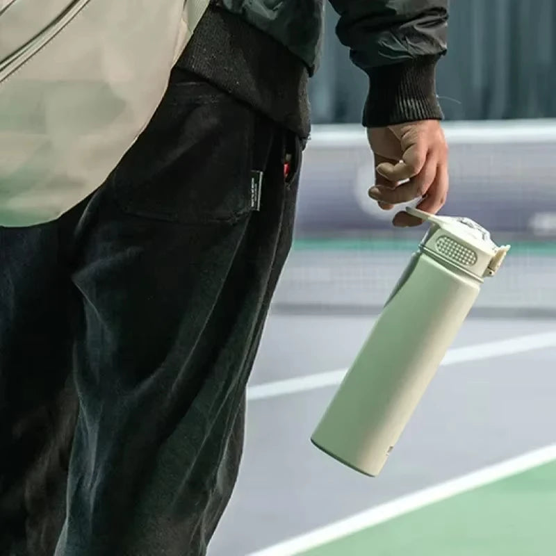 Bouteille portable Isotherme avec Paille beige tenue à la main pour une hydratation pratique en déplacement