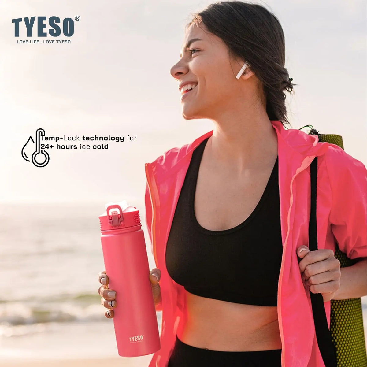 Femme souriante avec une gourde isotherme inox 600ml 750ml sport à la plage, idéale pour garder les boissons froides