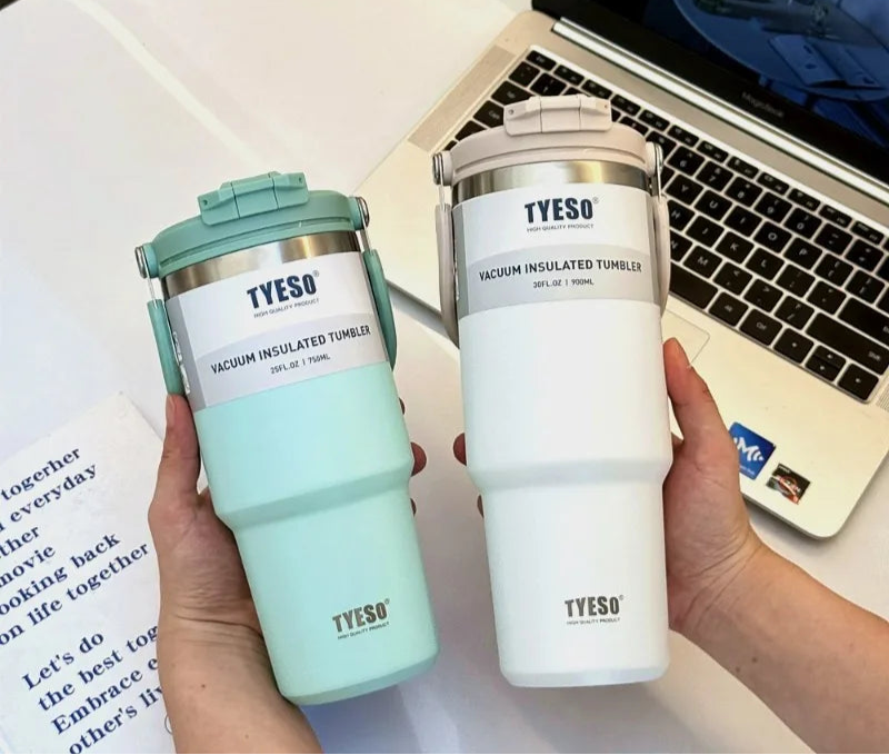 Deux mugs isothermes TYESO tenus à la main près d'un ordinateur portable Mug isotherme inox avec anse – 750ml à 1200ml