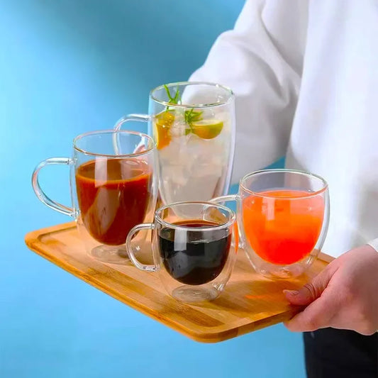 Quatre verres avec double paroi pour boissons chaudes et froides, présentés sur un plateau en bois