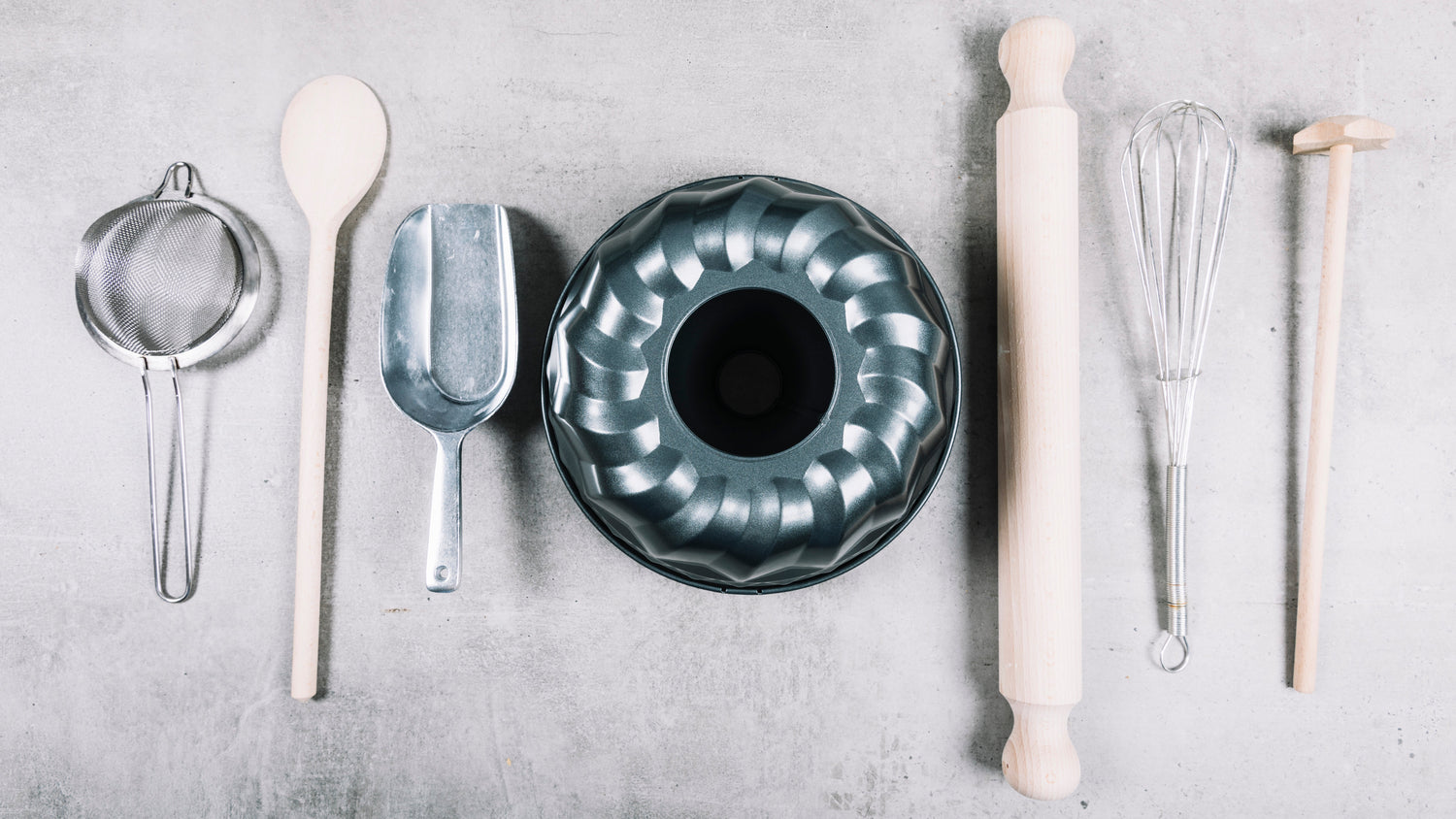 Ustensiles de préparation pâtisserie avec bols gradués, fouets inox et cuillères doseuses remplis d'ingrédients pour recettes