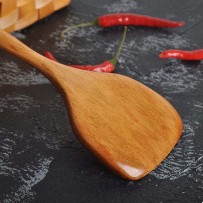 Spatule en Bois Long Manche – Ustensile de Cuisine Durable en bois verni manche long posée sur plan sombre avec piments
