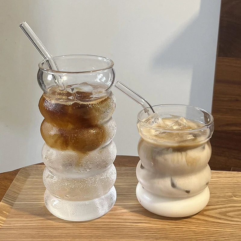 Verre Tumbler Ondulé Transparent – Élégant & Pratique. Deux tumblers ondulés avec glaçons et pailles en verre sur plateau