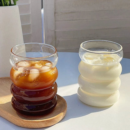 Verre Tumbler Ondulé Transparent – Élégant & Pratique. Deux verres ondulés transparents, café glacé et lait frais sur table.