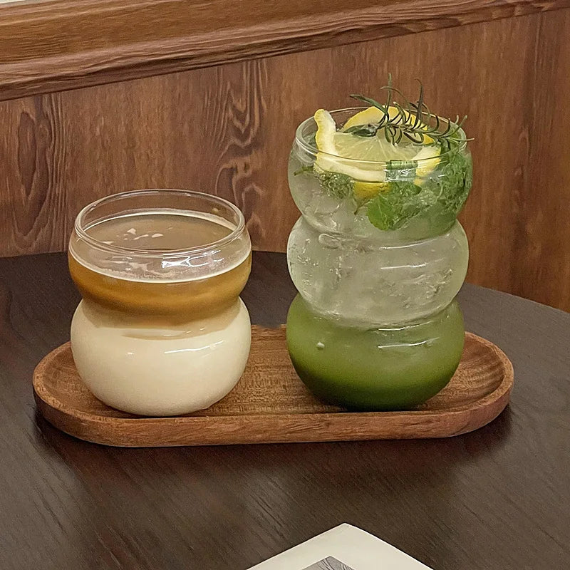 Verre Tumbler Ondulé Transparent – Élégant & Pratique. Deux verres ondulés sur plateau en bois avec café et boisson citronnée