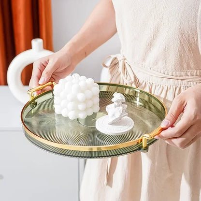 Mains tenant un Plateau Rond Acrylique avec Poignées Dorées – Déco & Service affichant bougie bulle blanche et figurine décorative