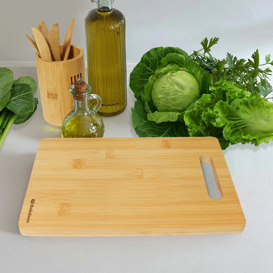 Planche à découper bambou avec une surface lisse, entourée de légumes frais et d'ustensiles de cuisine en bois