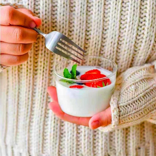Une personne dégustant un dessert dans un bol à dessert en verre avec des fraises et de la menthe