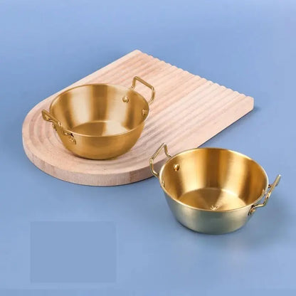 Bol Inox Doré avec Anse Anti brûlure – 12 à 14 cm posé sur surface bleue avec plateau en bois