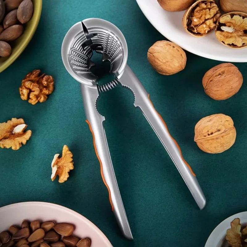 Casse-Noix à Ressort en aluminium avec noix, noisettes et amandes sur une table en vert
