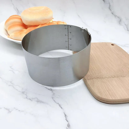 Cercle à Gâteau Réglable Inox – Rond ou Carré posé sur une surface en bois avec des petits pains en arrière-plan
