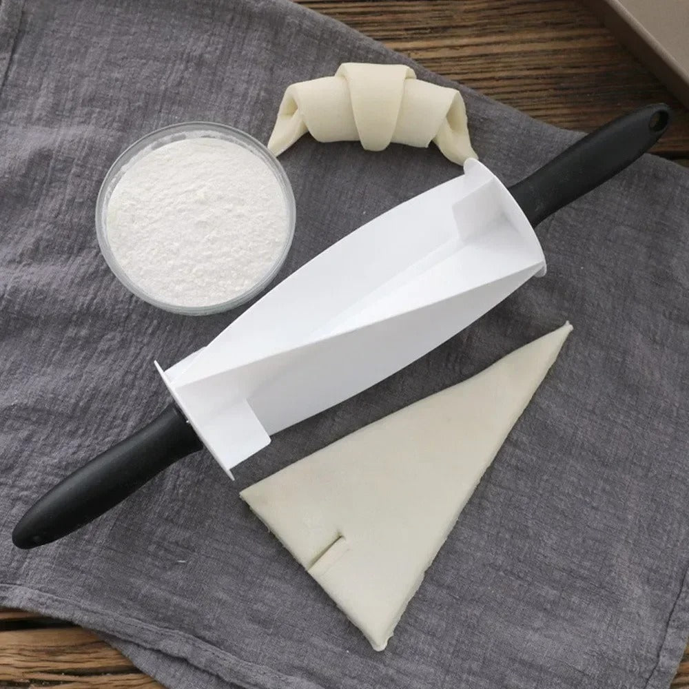 Coupe-Pâte à Croissants – Rouleau de Découpe avec pâte, croissant et farine sur un tissu de cuisine.