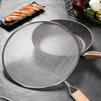 Couvercle Anti-Projections Inox – 21 à 33 cm posé à côté d'une poêle avec poignée en bois et crevettes