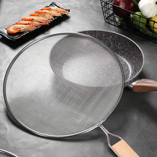 Couvercle Anti-Projections Inox – 21 à 33 cm posé à côté d'une poêle avec poignée en bois et crevettes