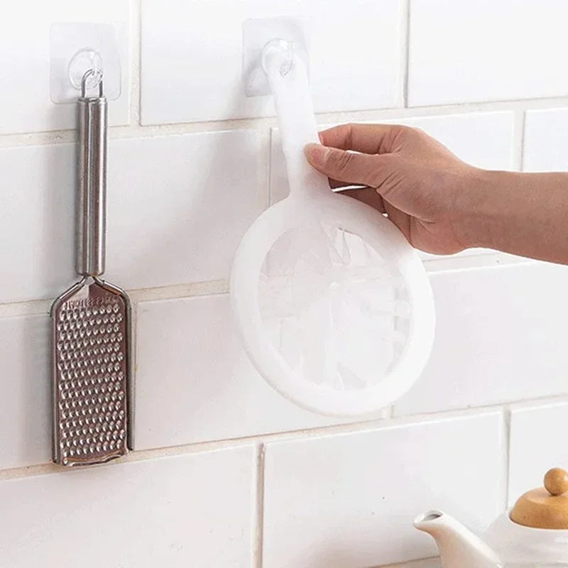 Main tenant une passoire blanche accrochée au mur près d'une râpe Passoire fine nylon & PP – Filtration précise et durable.