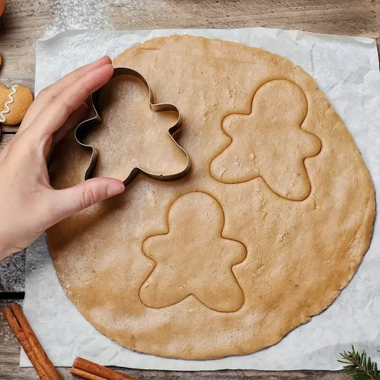 Emporte-Pièce Bonhomme en Pain d’Épices – Inox découpant des formes dans la pâte à biscuits sur un plan de travail en bois