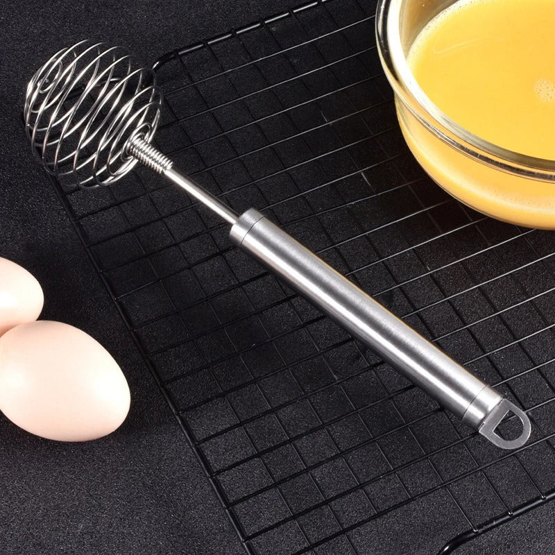 Fouet à Ressort en Inox – Batteur Manuel pour Cuisine et Pâtisserie sur une grille avec des œufs et un bol