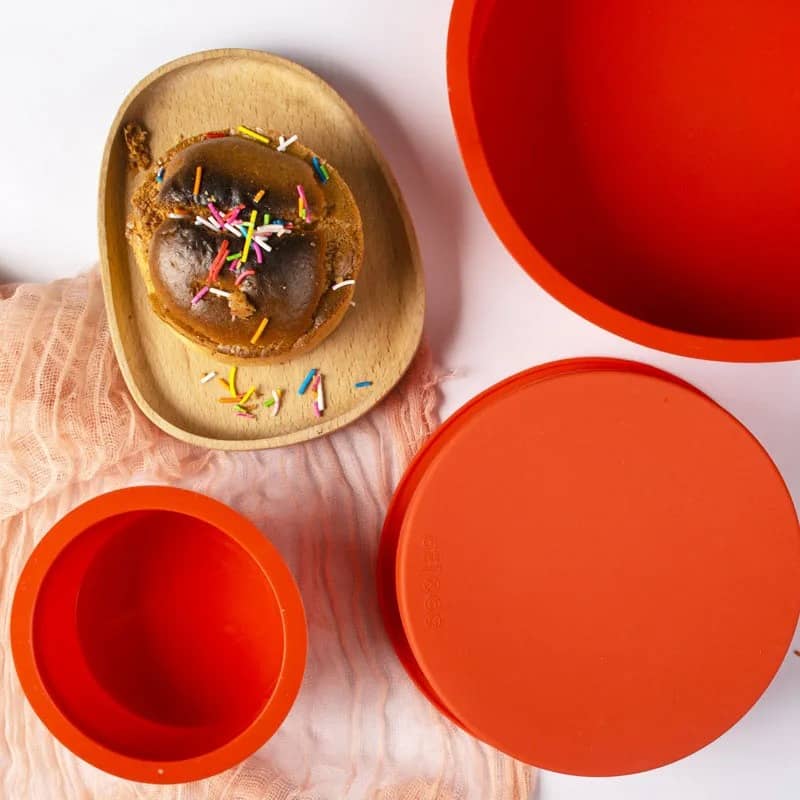 Trois moules à gâteau en silicone orange de Ustensiles de chef avec un dessert décoré de vermicelles colorés